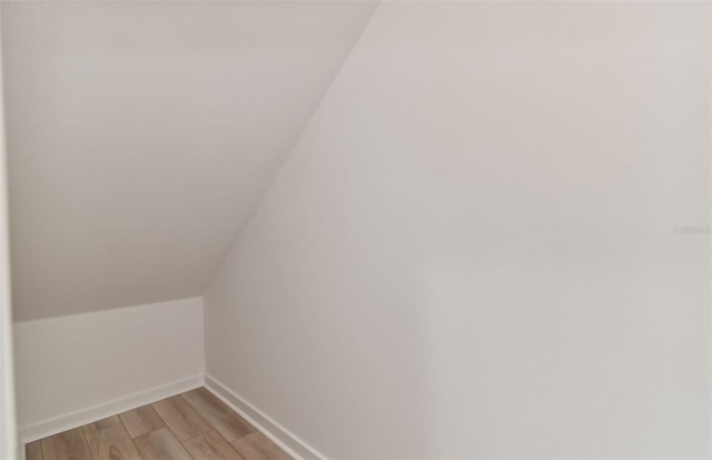 additional living space featuring lofted ceiling, baseboards, and light wood finished floors