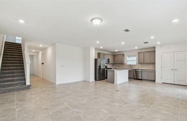 10410 Cross River Trl, Parrish, FL 34219 - kitchen with appliances with stainless steel finishes, gray cabinetry, tasteful backsplash, light countertops, and a kitchen island