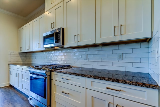 kitchen with white cabinetry, appliances with stainless steel finishes, dark stone counters, and crown molding