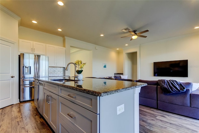 kitchen with a center island with sink, visible vents, appliances with stainless steel finishes, open floor plan, and a sink