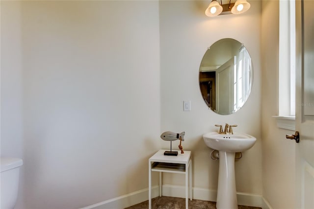 bathroom with a chandelier, toilet, and baseboards