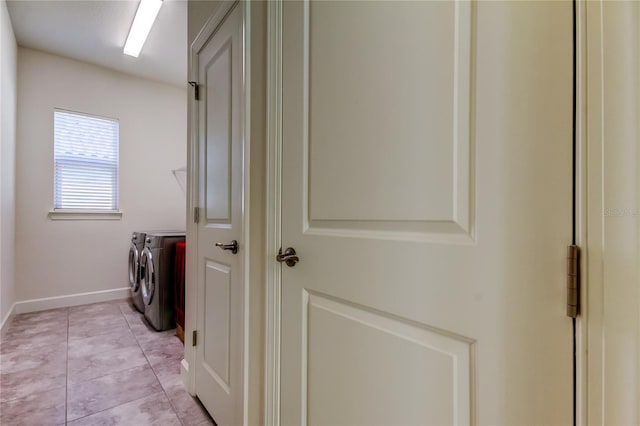 laundry room with laundry area, separate washer and dryer, light tile patterned flooring, and baseboards