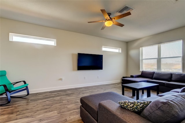 living area featuring visible vents, wood finished floors, a wealth of natural light, and baseboards