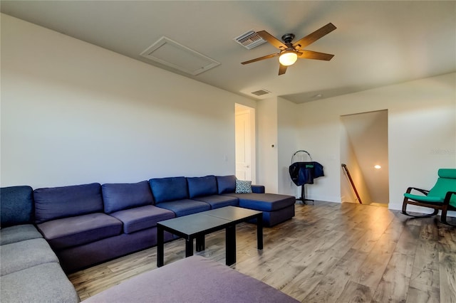 living room with a ceiling fan, baseboards, visible vents, light wood-style floors, and attic access