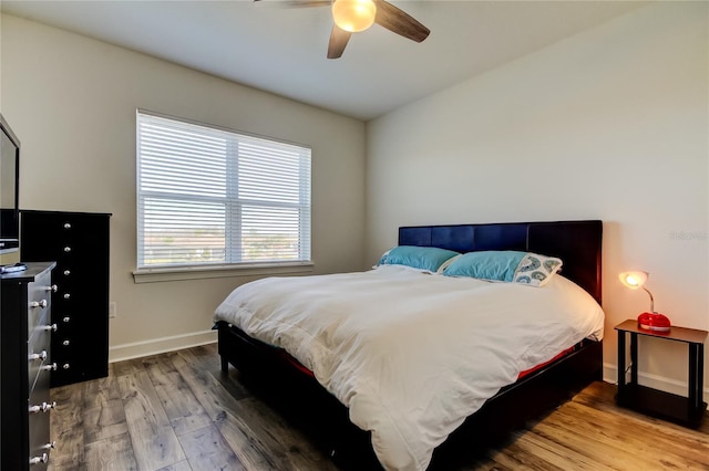 bedroom with ceiling fan, baseboards, and wood finished floors