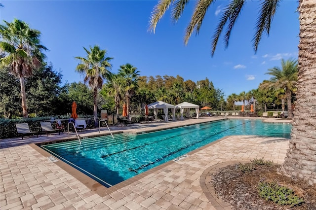 community pool with a patio area, fence, and a gazebo