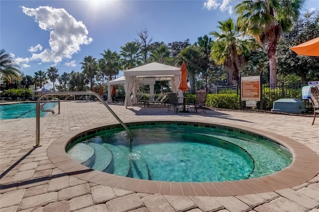 view of pool with a gazebo, a community hot tub, and fence