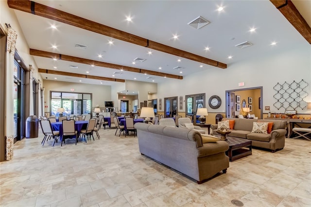 living room with beam ceiling, visible vents, and a towering ceiling