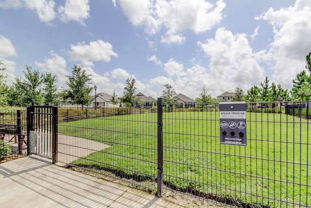 view of gate featuring a residential view, a yard, and fence