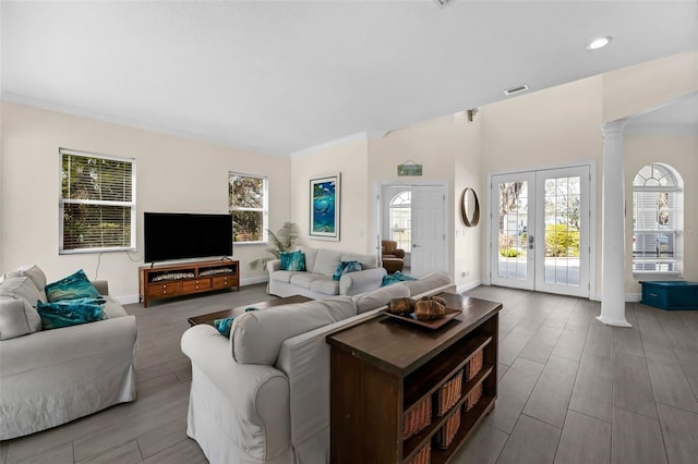 living area with wood finished floors, visible vents, french doors, ornamental molding, and ornate columns