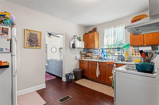 kitchen with white appliances, visible vents, brown cabinets, range hood, and light countertops