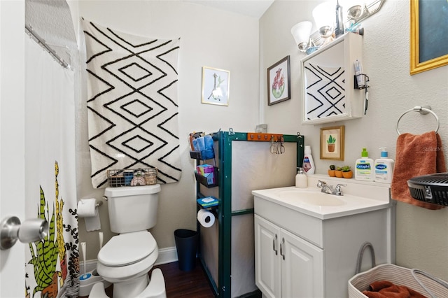 bathroom with baseboards, toilet, wood finished floors, an inviting chandelier, and vanity