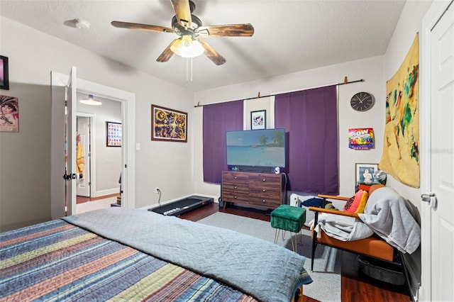 bedroom featuring baseboards, a textured ceiling, a ceiling fan, and wood finished floors