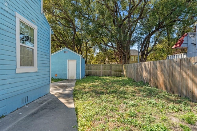 view of yard featuring a fenced backyard, a storage unit, and an outdoor structure