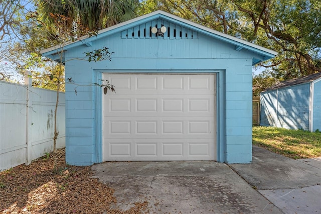 detached garage featuring driveway and fence