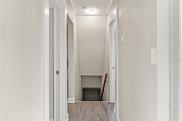 corridor with ornamental molding, wood finished floors, and an upstairs landing