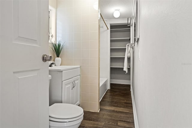 full bathroom with tile walls, toilet, vanity, a textured ceiling, and wood finished floors