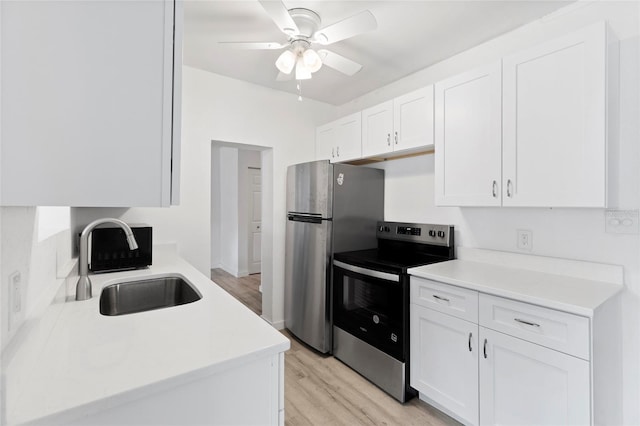 kitchen featuring light countertops, white cabinets, stainless steel appliances, a ceiling fan, and a sink