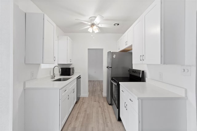 kitchen with a ceiling fan, a sink, appliances with stainless steel finishes, white cabinets, and light wood finished floors