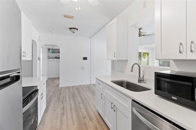 kitchen with a sink, black appliances, ceiling fan, and light countertops