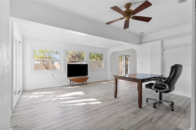 office featuring arched walkways, visible vents, light wood-type flooring, and a ceiling fan