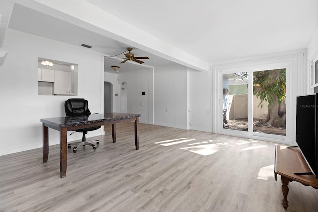 home office with a ceiling fan, visible vents, baseboards, light wood-style flooring, and arched walkways