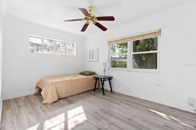 bedroom featuring ceiling fan, baseboards, light wood-style flooring, and crown molding