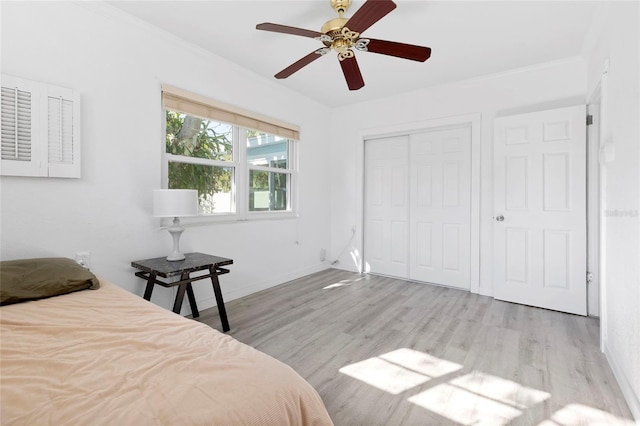 bedroom featuring wood finished floors, a closet, crown molding, baseboards, and ceiling fan