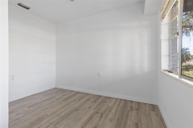 empty room featuring visible vents, baseboards, and wood finished floors