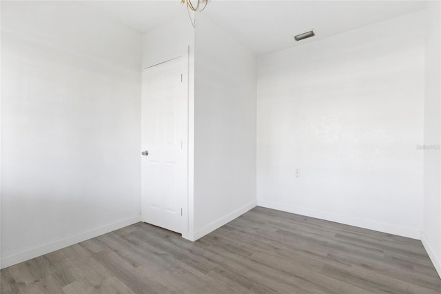 spare room with visible vents, baseboards, and wood finished floors