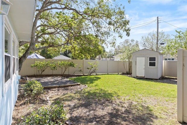 view of yard featuring a storage shed, an outbuilding, and a fenced backyard