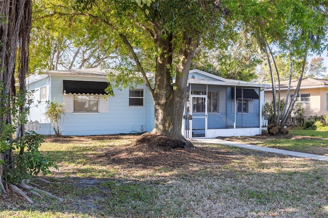 single story home featuring a front lawn and a sunroom