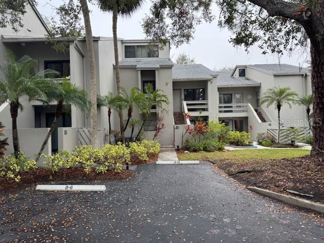 view of front of property featuring stairs, uncovered parking, and stucco siding