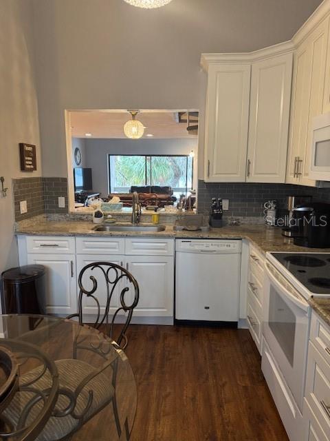 kitchen featuring light stone counters, white appliances, a sink, and white cabinetry