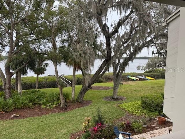 view of home's community with a water view and a lawn