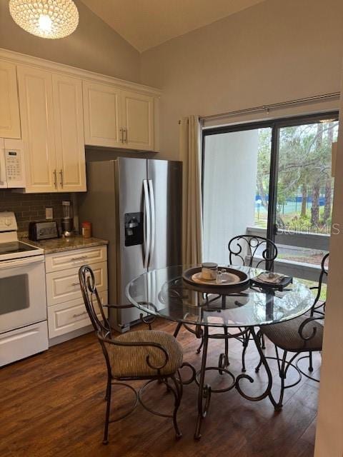 kitchen with white appliances, vaulted ceiling, white cabinets, and dark wood-style flooring