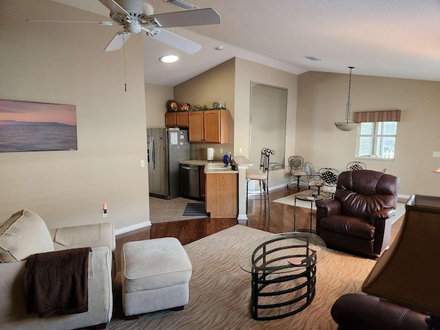 living room with lofted ceiling, a ceiling fan, light wood-style flooring, and baseboards