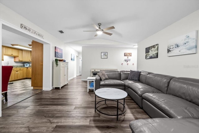 living area featuring visible vents, lofted ceiling, dark wood-style floors, baseboards, and ceiling fan