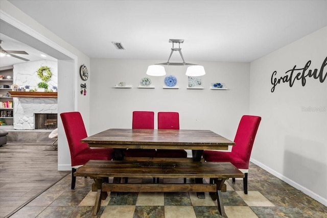 dining area with visible vents, baseboards, and a stone fireplace