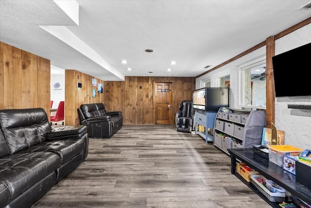 living area with wooden walls, recessed lighting, a textured ceiling, and wood finished floors