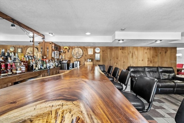 interior space featuring a bar, wooden walls, and a textured ceiling