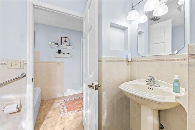 bathroom with a wainscoted wall, visible vents, a sink, tile patterned flooring, and tile walls