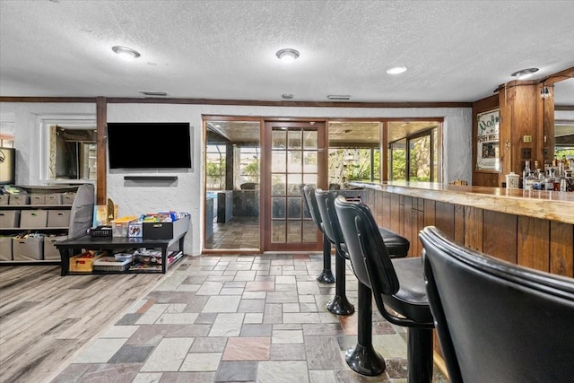 interior space featuring visible vents, stone finish floor, a dry bar, and a textured ceiling