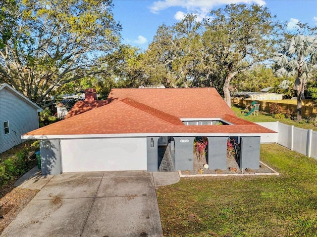 view of front facade with a front yard, fence, a shingled roof, concrete driveway, and a garage