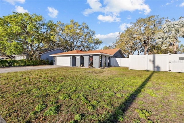 view of yard featuring concrete driveway, fence, and a garage