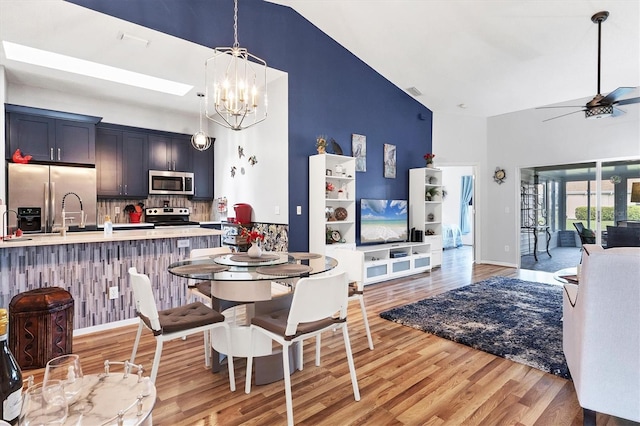 dining room with light wood-style flooring, visible vents, high vaulted ceiling, and ceiling fan with notable chandelier