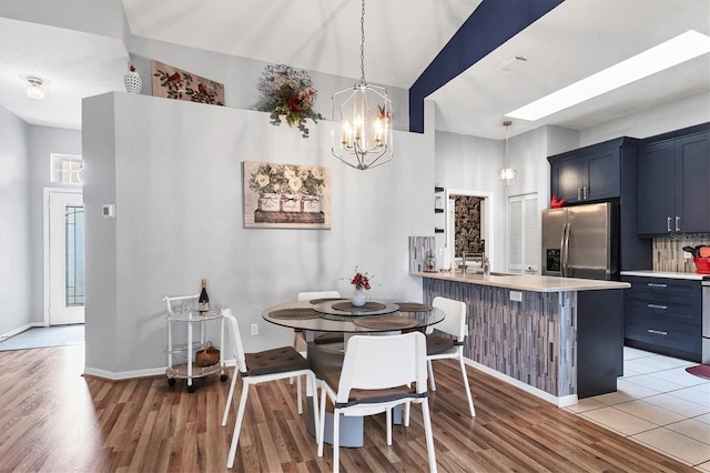 dining area featuring a chandelier, light wood-type flooring, visible vents, and baseboards