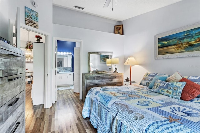 bedroom with visible vents, connected bathroom, a textured ceiling, and wood finished floors