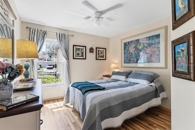 bedroom with light wood-type flooring, a ceiling fan, and baseboards