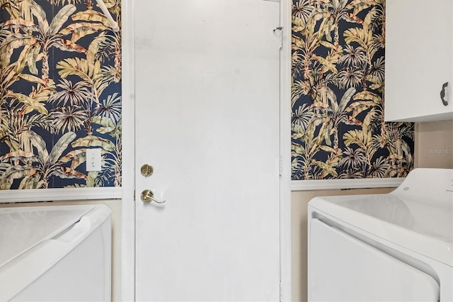 washroom featuring cabinet space, wallpapered walls, and washer and dryer